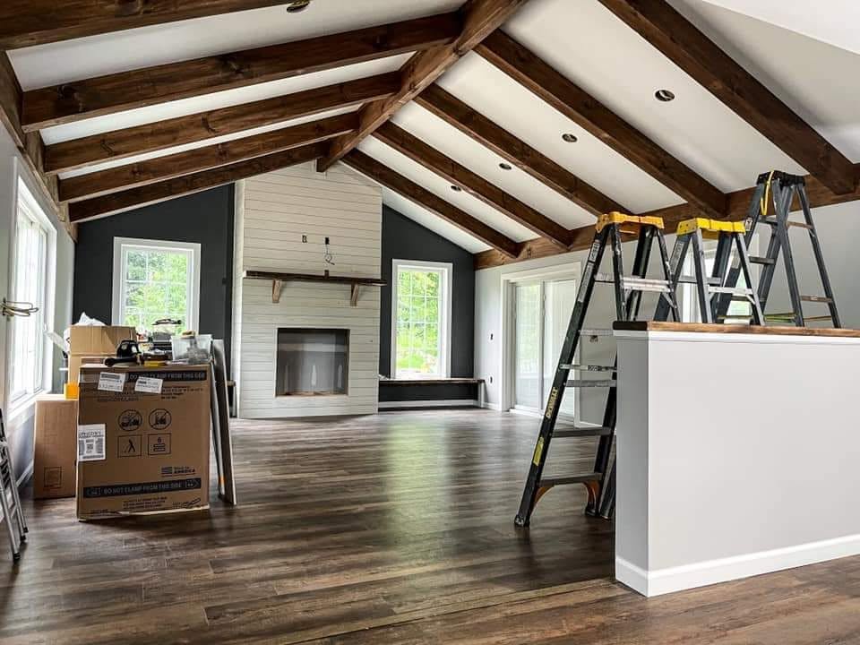Freshly finished living room with vaulted wood-beam ceiling and crisp white trim